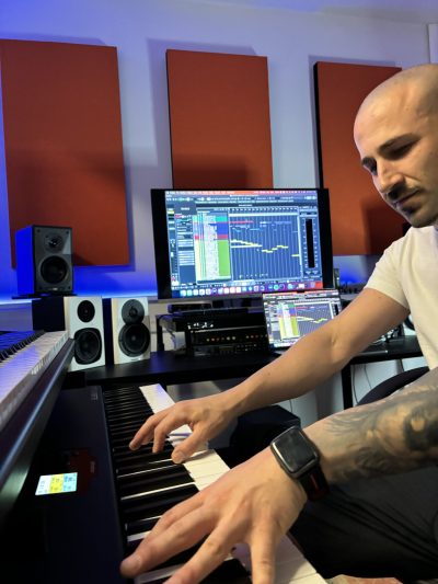 Fabrizio Ranzani che compone musica al pianoforte nel suo studio di registrazione, con monitor che mostrano tracce musicali su Cubase Pro 12.